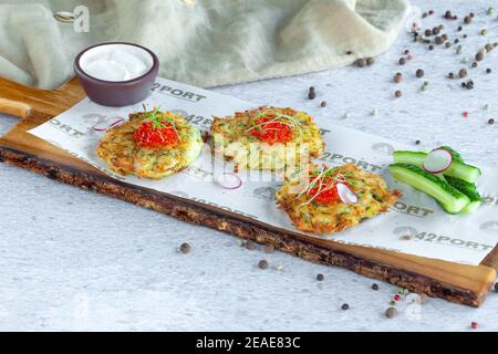 Russische gebratene traditionelle Vorspeise draniki - Kartoffelpfannkuchen, roter Kaviar Stockfoto