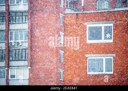 Fenster und Balkone der sowjetischen Blöcke Gebäude mit roten Ziegeln während des großen Schneefalls in der Stadt Vilnius, Litauen im Winter Stockfoto