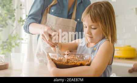 In der Küche: Porträt der niedlichen kleinen Tochter Mischen Mehl und Wasser zu Teig für Cupcakes zu erstellen. Familie Kochen Muffins Zusammen. Bezaubernd Stockfoto