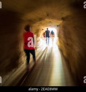 Zwei Frauen, die an einem sonnigen Tag durch einen Tunnel in den Bergen des Naturparks der Gaitanes-Schlucht in Malaga fahren. Stockfoto