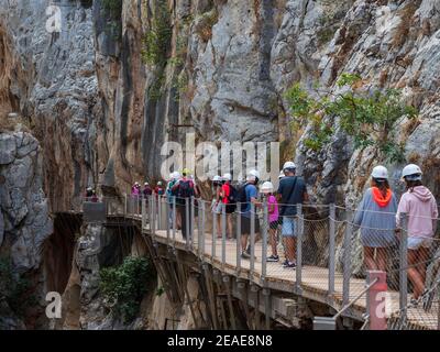 Wandergruppe mit Helm und Masken entlang des Caminito del Rey in der Gaitanes-Schlucht in Malaga. Stockfoto