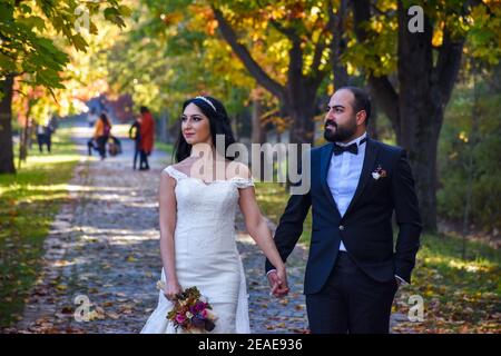 Wunderschönes Hochzeitspaar, das im Park, Istanbul, Türkei, spazieren geht Stockfoto