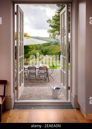 Offene französische Fenster führen zu einem Sitzbereich auf der Terrasse eines modernen Hauses in Sussex, Großbritannien Stockfoto