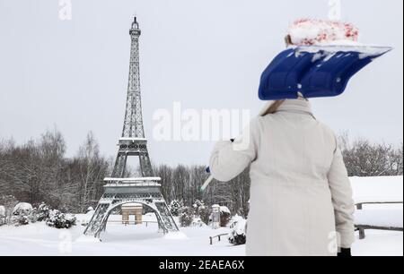 Sachsen, Lichtenstein/Sachsen, 09. Februar 2021: Vor dem Eiffelturm in der Miniwelt steht ein Mitarbeiter mit Schneebesen und Schneeschaufel. Um Schäden im Winter zu vermeiden, sind einige der Denkmäler eingezäunt. Die anderen werden regelmäßig kontrolliert und von Schnee befreit. Die Schneelast und vor allem der Wechsel zwischen Tauwetter und Frost ist ein Problem. Wasser dringt zwischen die filigranen Steine ein und bläst sie ab. Quelle: dpa picture Alliance/Alamy Live News Quelle: dpa picture Alliance/Alamy Live News Stockfoto