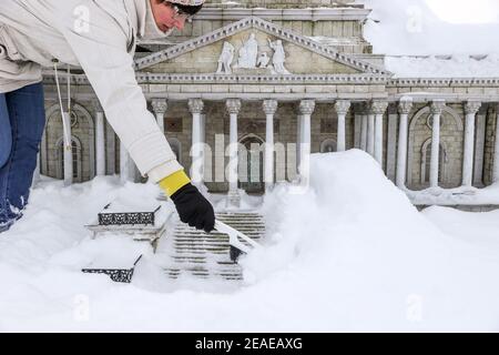 Sachsen, Lichtenstein/Sachsen,09. Februar 2021: Ein Mitarbeiter räumt Schnee aus dem Washington DC Capitol in Miniworld. Um Schäden im Winter zu vermeiden, sind einige der Denkmäler eingezäunt. Der Rest wird regelmäßig kontrolliert und von Schnee befreit. Die Schneelast und vor allem der Wechsel zwischen Tauwetter und Frost ist ein Problem. Wasser dringt zwischen die filigranen Steine ein und bläst sie ab. Im Vergnügungspark befinden sich über 100 weltberühmte Denkmäler im Maßstab 1:25. Fast 2 Millionen Menschen haben die Mini-Welt bereits besucht. Foto: Jan Woitas/dpa-Zentralbild/dpa Quelle: dpa picture Alliance/Alam Stockfoto