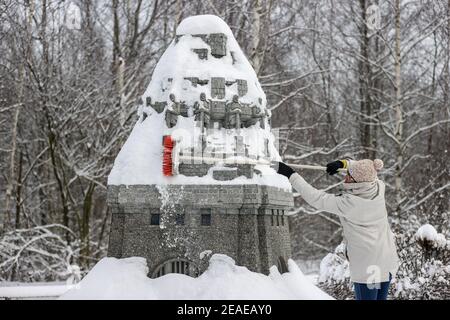 Sachsen, Lichtenstein/Sachsen,09. Februar 2021: Ein Mitarbeiter entfernt Schnee aus dem Völkerschlachtdenkmal in der Miniwelt. Um Schäden im Winter zu vermeiden, sind einige der Denkmäler eingezäunt. Die anderen werden regelmäßig kontrolliert und von Schnee befreit. Die Schneelast und vor allem der Wechsel zwischen Tauwetter und Frost ist ein Problem. Wasser dringt zwischen die filigranen Steine ein und bläst sie ab. Im Vergnügungspark befinden sich über 100 weltberühmte Denkmäler im Maßstab 1:25. Fast 2 Millionen Menschen haben die Mini-Welt bereits besucht. Foto: Jan Woitas/dpa-Zentralbild/dpa Kredit: dpa pic Stockfoto