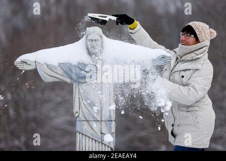 Sachsen, Lichtenstein/Sachsen,09. Februar 2021: Ein Mitarbeiter befreit die Statue 'Cristo Redentor' aus Rio de Janeiro vom Schnee in der Miniwelt. Um Schäden im Winter zu vermeiden, sind einige der Denkmäler eingezäunt. Die anderen werden regelmäßig kontrolliert und von Schnee befreit. Die Schneelast und vor allem der Wechsel zwischen Tauwetter und Frost ist ein Problem. Wasser dringt zwischen die filigranen Steine ein und bläst sie ab. Im Vergnügungspark befinden sich über 100 weltberühmte Denkmäler im Maßstab 1:25. Fast 2 Millionen Menschen haben die Mini-Welt bereits besucht. Foto: Jan Woitas/dpa-Zentralbild/dpa Cred Stockfoto