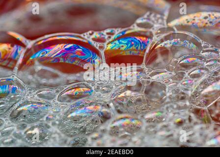 Große Seifenblasen mit einem mehrfarbigen Regenbogenmuster. Schwimmend auf dem Wasser. Eine Textur bilden. Abstrakter Hintergrund. Stockfoto