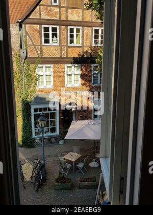 LÜNEBURG, NIEDERSACHSEN, DEUTSCHLAND - 27. JULI 2018: Blick vom Hotelfenster auf einen kleinen Marktplatz und eine Kaffeerösterei in Lüneburg Stockfoto