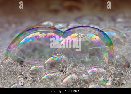 Nahaufnahme von großen farbigen Seifenblasen mit einem Regenbogenmuster. Schwimmend auf dem Wasser. Abstrakter Hintergrund. Stockfoto