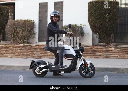 Junge auf einem Elektromotorrad. Reiten mit Helm und schwarzer Kleidung. Ökologisches Transportkonzept. Keine Verschmutzung. Stockfoto