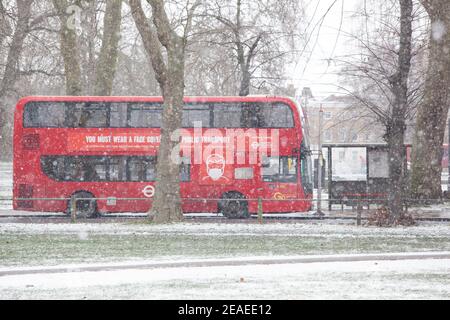 London, Großbritannien. 9. Februar 2021: Nach drei Tagen Schnee in London beginnt es sich zu beruhigen und die Winde sind gefallen, als Storm Darcy vorbei ist. Auf Clapham Common nehmen einige Leute Übung und vorbeifahrende Busse tragen Nachrichten über das Tragen von Gesichtsbedeckungen. Quelle: Anna Watson/Alamy Live News Stockfoto