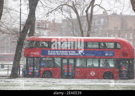 London, Großbritannien. 9. Februar 2021: Nach drei Tagen Schnee in London beginnt es sich zu beruhigen und die Winde sind gefallen, als Storm Darcy vorbei ist. Auf Clapham Common nehmen einige Leute Übung und vorbeifahrende Busse tragen Nachrichten über das Tragen von Gesichtsbedeckungen. Quelle: Anna Watson/Alamy Live News Stockfoto