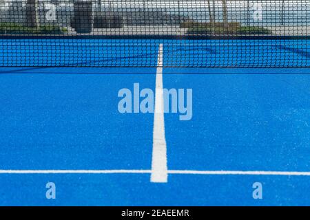 Hellblaue Tennis-, Paddle- oder Pickleball-Court Bodenansicht mit weißer Linie in Richtung schwarzes Netz im Freien. Stockfoto