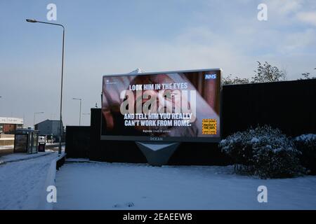 Glasgow, Großbritannien, am 9. Februar 2021. Öffentliche Informationsanzeigen spielen auf einer elektronischen Plakatwand, auf einer verlassenen Straße, nach dem Schneehön der Vornacht. Glasgow bleibt während der laufenden Covid-19-Coronavirus-Gesundheitspandemie weiterhin in der Sperre. Foto: Jeremy Sutton-Hibbert/ Alamy Live News. Stockfoto