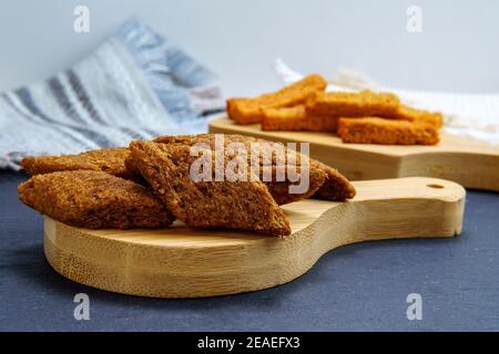 Dunkle Croutons aus der Nähe auf einem Holzbrett. Nahaufnahme. Selektiver Fokus. Stockfoto