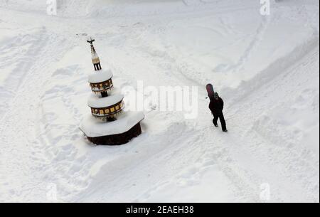 Wernigerode, Deutschland. Februar 2021, 08th. Ein Passant spaziert mit einem Snowboard über den schneebedeckten Marktplatz am Marktbrunnen vorbei. Quelle: Matthias Bein/dpa-Zentralbild/dpa/Alamy Live News Quelle: dpa picture Alliance/Alamy Live News Stockfoto