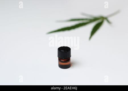 Cannabisöl. Marihuanaöl in einer Flasche mit einem Deckel. Verschwommenes Marihuana medizinisches Cannabisblatt auf dem Hintergrund. Minimalistisches Konzept. Einfachheit Stockfoto