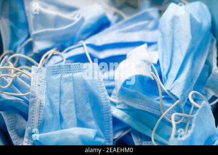 Nahaufnahme viele blaue Gesichtsmasken auf dem Hintergrund. Blauer medizinischer Hintergrund. Die Herstellung von Masken gegen das Coronavirus covid 19. Sicherheit und Stockfoto