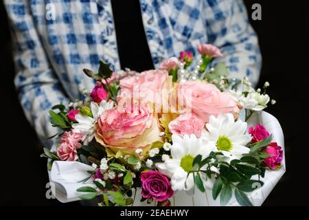 Der Mensch schenkt Blumen. Geschenkbox mit Blumen. Nahaufnahme der Box mit rosa Rosen in männlichen Händen. Männlich Geschenk für Muttertag, Valentinstag, Frauen Tag Stockfoto