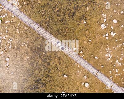 Luftaufnahme von oben nach unten von einem verliebten jungen Paar, das auf einer Holzbrücke über den Fluss liegt. Luftaufnahme. Stockfoto