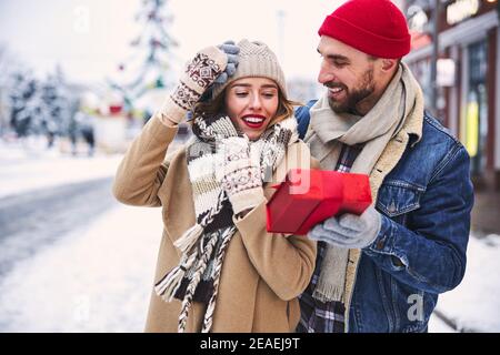 Liebevoller Mann macht Geschenk für Freundin im Freien Stockfoto