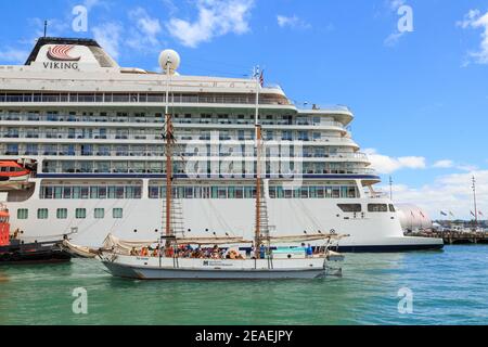 Ein altmodischer Scow, der 'Ted Asby', der an einem modernen Kreuzfahrtschiff, dem 'Viking Orion', vorbeisegelt. Waitemata Harbour, Auckland, Neuseeland Stockfoto