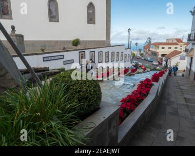 Firgas, Gran Canaria, Kanarische Inseln, Spanien 13. Dezember 2020: Blick auf die Straße Paseo de Gran Canaria mit Wasserfall Brunnen, Blumen und Keramik Stockfoto