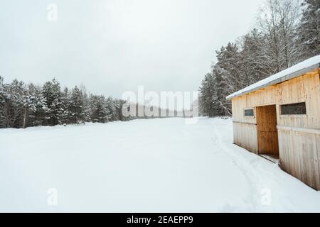 Der Hintergrund eines Winterwaldes, eine Landschaft von Tannen mit weißem Schnee, eine leere Straße zwischen tiefen Schneeverwehungen in einem Schneesturm Stockfoto