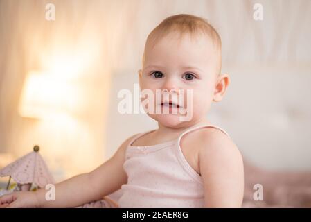 Nette glückliche 1 Jahre alte Baby-Mädchen spielen mit Holzspielzeug zu Hause. Modernes Kinderzimmer-Interieur, frühes Lernkonzept Stockfoto