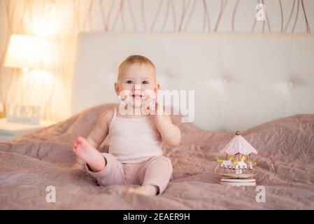 Nettes Baby Mädchen spielen mit Holzspielzeug zu Hause Schlafzimmer. Moderne Kinderzimmer-Innenausstattung in rosa Farbe Stockfoto