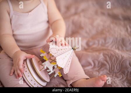 Nettes Baby Mädchen spielen mit Holzspielzeug zu Hause Schlafzimmer. Moderne Kinderzimmer-Innenausstattung in rosa Farbe Stockfoto