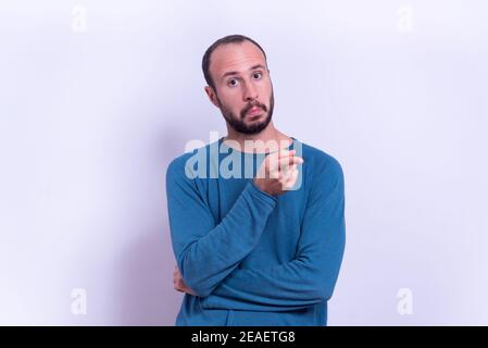 Junger Mann zeigt Finger auf Kamera im Studio-Porträt auf blauem Hintergrund mit überrascht und erstaunt Ausdruck. Beeindruckt Mann zeigt Finger Stockfoto