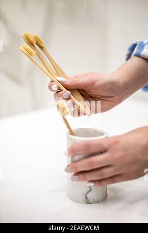 Frau organisiert Umwelt Badezimmer Annehmlichkeiten in Schublade und setzen Bambus Zahnbürste in eine Tasse Stockfoto