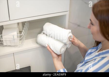 Frauen Hände ordentlich Putting oder Anzeige einer sauberen aufgerollten weißen Handtücher aus Bio-Baumwolle. Stockfoto