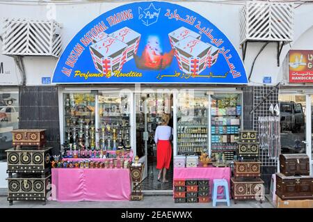 Schaufenster & Waren Rückansicht der Frau, die einen betritt Shop Front Verkauf Parfüms & Neuheiten auf corniche Straße in Mutrah Muscat Oman Mittlerer Osten Stockfoto