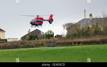 Devon Air Ambulance Hubschrauber Start von einem Feld neben Häusern. Stockfoto