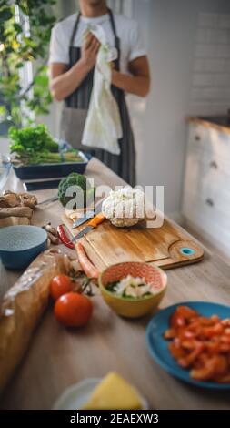 Aufnahme eines Küchentisch mit Gemüse und Blumenkohl auf einem Schneidebret. Gesunde Bio-Green Food in einer modernen sonnigen Küche. Natürliche Saubere Ernährung Stockfoto