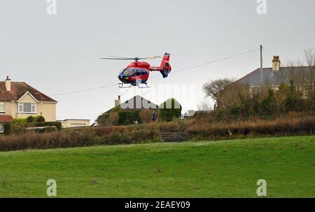 Devon Air Ambulance Hubschrauber Start von einem Feld neben Häusern. Stockfoto