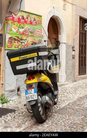 Piaggio Liberty Roller in der Poste Italiane S.p.A. Lackierung vor einem Geschäft in Malcesine, Gardasee, Italien geparkt. Stockfoto