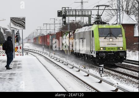 Berlin, Deutschland. Februar 2021, 09th. Ein Güterzug fährt an einem Bahnhof vorbei, an dem eine Person auf die S-Bahn wartet. Derzeit gibt es wetterbedingte Einschränkungen im gesamten Schienennetz. Quelle: Kira Hofmann/dpa-Zentralbild/dpa/Alamy Live News Stockfoto