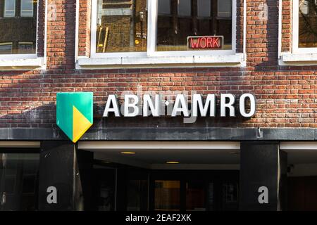 Utrecht, Niederlande, Januar 24 2021: ABN Amro Bank Closeup Inschrift auf einem Gebäude und das Wort Arbeit rot-beleuchtet darüber Stockfoto