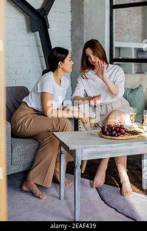 Zwei Frau Klatsch Blick auf Smartphone e Dating oder online Shopping Anwendung Champagner trinken Stockfoto