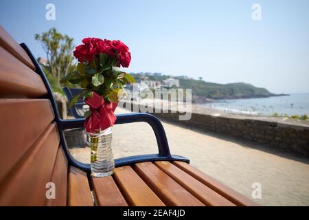 Foto eines Blumendenkmals auf einer öffentlichen Bank in Langland Bay, Gower Peninsula, Wales. Stockfoto