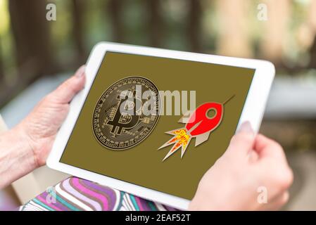 Weibliche Hände halten eine Tablette mit Bitcoin Wachstum Konzept Stockfoto