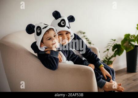 Zwei niedliche kleine Brüder in kigurumi von Panda Stockfoto