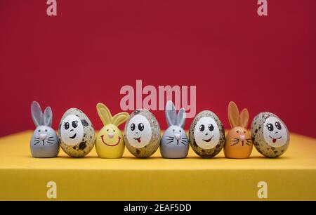 Bunte niedliche Osterhasen, Osterquageleier mit gemaltem Lächeln und Augen stehen nebeneinander in einer Reihe. Lustige Dekorationen für das Frühlingsholid Stockfoto