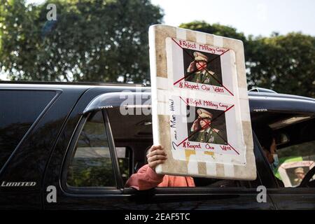 Ein Protestler hält ein Plakat durch ein Fahrzeugfenster mit Porträts von General Min Aung Hlaing, die am vierten Tag der Proteste gegen den Militärputsch durchgestrichen wurden. Tausende Menschen gingen am vierten Tag des Protests gegen den Militärputsch auf die Straßen von Yangon und forderten die Freilassung von Aung San Suu Kyi. Das Militär von Myanmar nahm am 01. Februar 2021 die staatliche Beraterin von Myanmar Aung San Suu Kyi fest und erklärte den Ausnahmezustand, während sie die Macht im Land für ein Jahr ergattete, nachdem sie die Wahl gegen die National League for Democracy (NLD) verloren hatte. Stockfoto