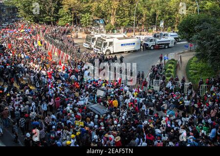 Die Polizei steht hinter einer gebildeten Barrikade und warnt die Menge der Demonstranten, sich am vierten Tag der Proteste gegen den Militärputsch entweder zu zerstreuen oder sich in Hledan mit Wasser besprühen zu lassen. Tausende Menschen gingen am vierten Tag des Protests gegen den Militärputsch auf die Straßen von Yangon und forderten die Freilassung von Aung San Suu Kyi. Das Militär von Myanmar nahm am 01. Februar 2021 die staatliche Beraterin von Myanmar Aung San Suu Kyi fest und erklärte den Ausnahmezustand, während sie die Macht im Land für ein Jahr ergattete, nachdem sie die Wahl gegen die National League for Democracy (NLD) verloren hatte Stockfoto