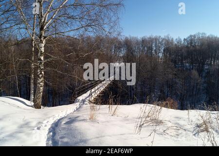 Die Landschaft mit Brücke durch Schlucht in Holz. Natur im Winter Länge der Zeit auf dem Hintergrund blauen Himmel Stockfoto